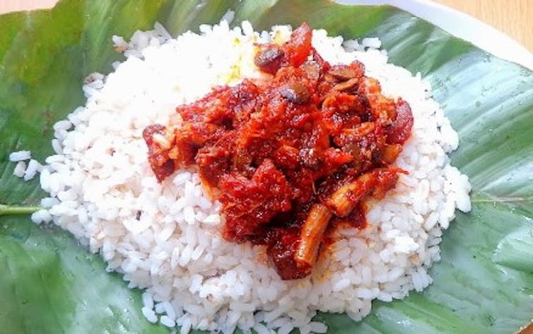 Plate of rice and stew served on a large green leaf