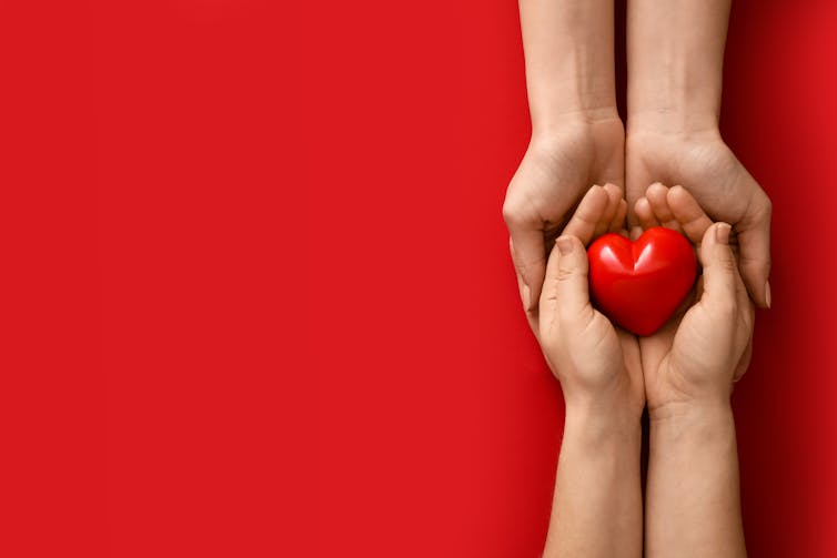 Hands with red heart on red background