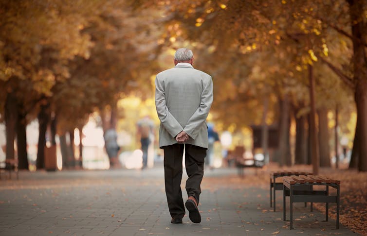 Hombre mayor paseando por el parque en otoño