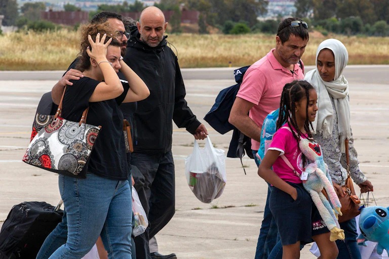 A group of people of all ages arrive in an airport.