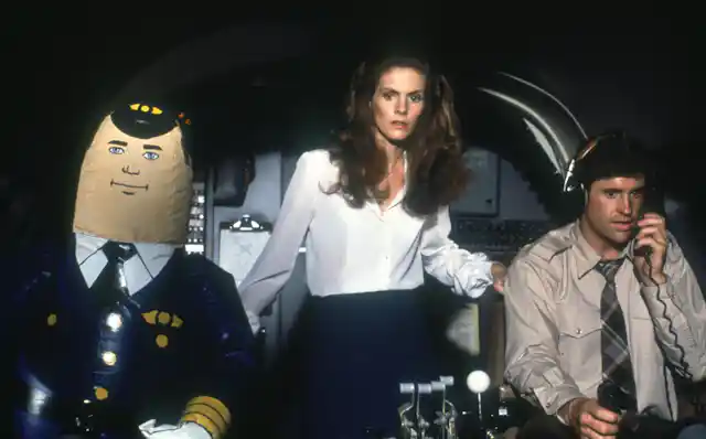 A blow-up autopilot, a sweating man and a woman looking scared are in an airplane cockpit!