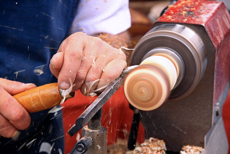 Hands of woodworker using a turning lathe.