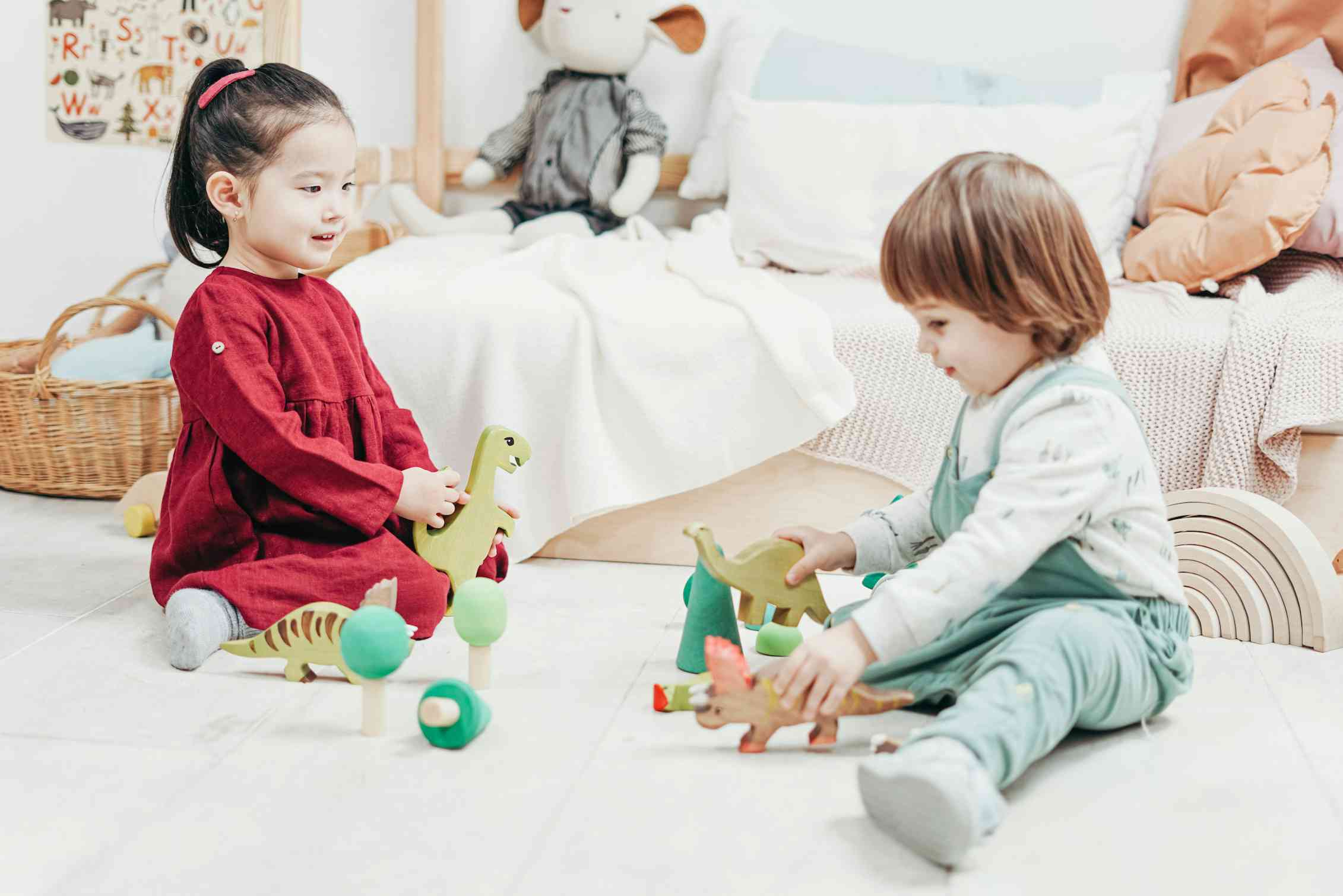 Two children seen sitting on a carpet playing