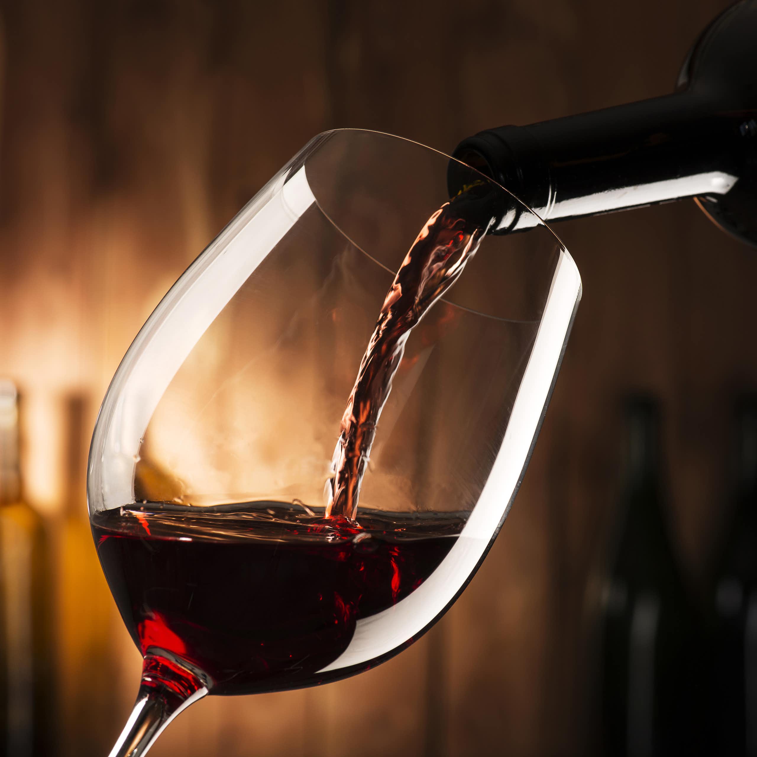 Du vin rouge passe d'une bouteille à un verre à pied