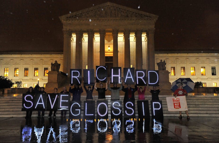 A group of people stand in front of the U.S. Supreme Court building holding signs that spell out "Save Richard Glossip"