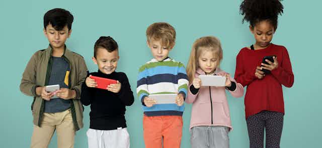 Children seen holding tech devices.