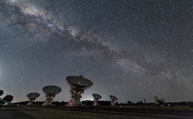A number of satellite dishes under the Milky Way.
