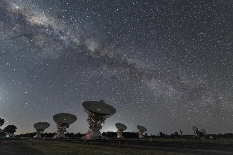 A number of satellite dishes under the Milky Way.