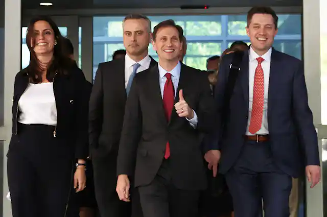 One woman and three men coming out of a door, smiling.