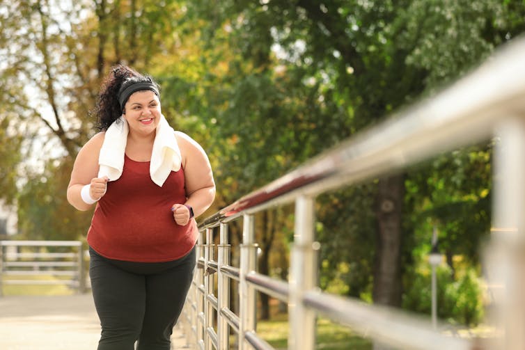 A woman in exercise gear outside, with a towel around her neck