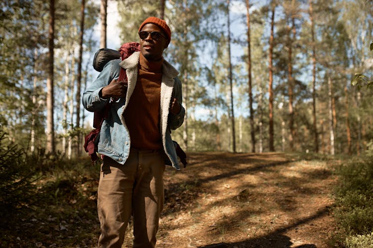 A man with a backpack standing on a wooded trail.