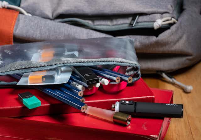 A school bag sits next to a pencil case with a vape spilling out of it.