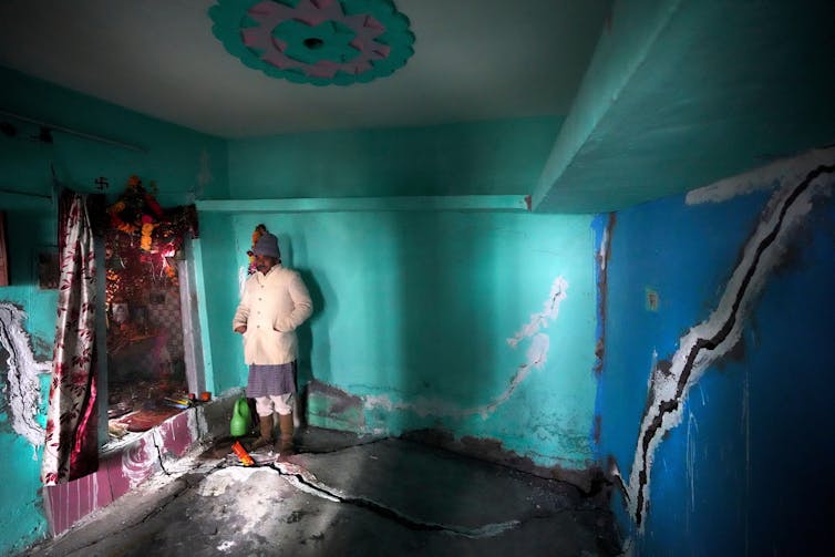 Homem na sala com parede rachada