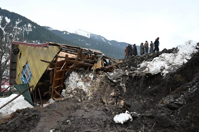 As pessoas olham para a casa desmoronada
