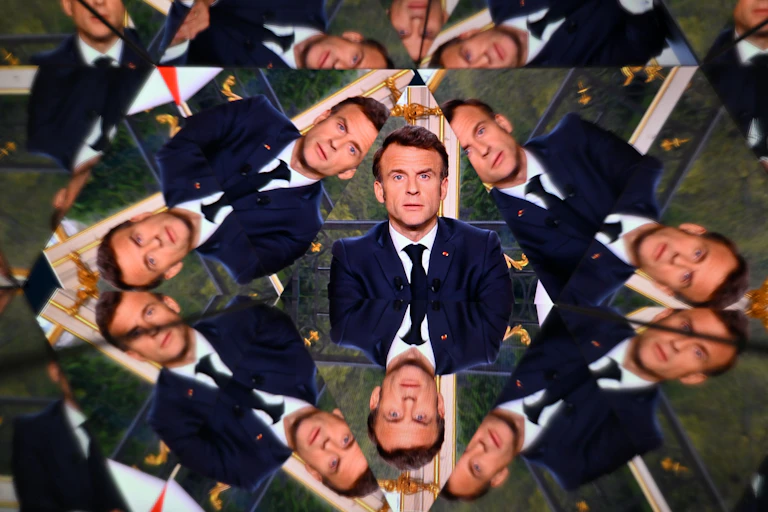 Le président français Emmanuel Macron apparaît sur un écran reflété par des miroirs lors d'une allocution télévisée à la nation, prononcée depuis le palais de l'Élysée, le 17 avril 2023.