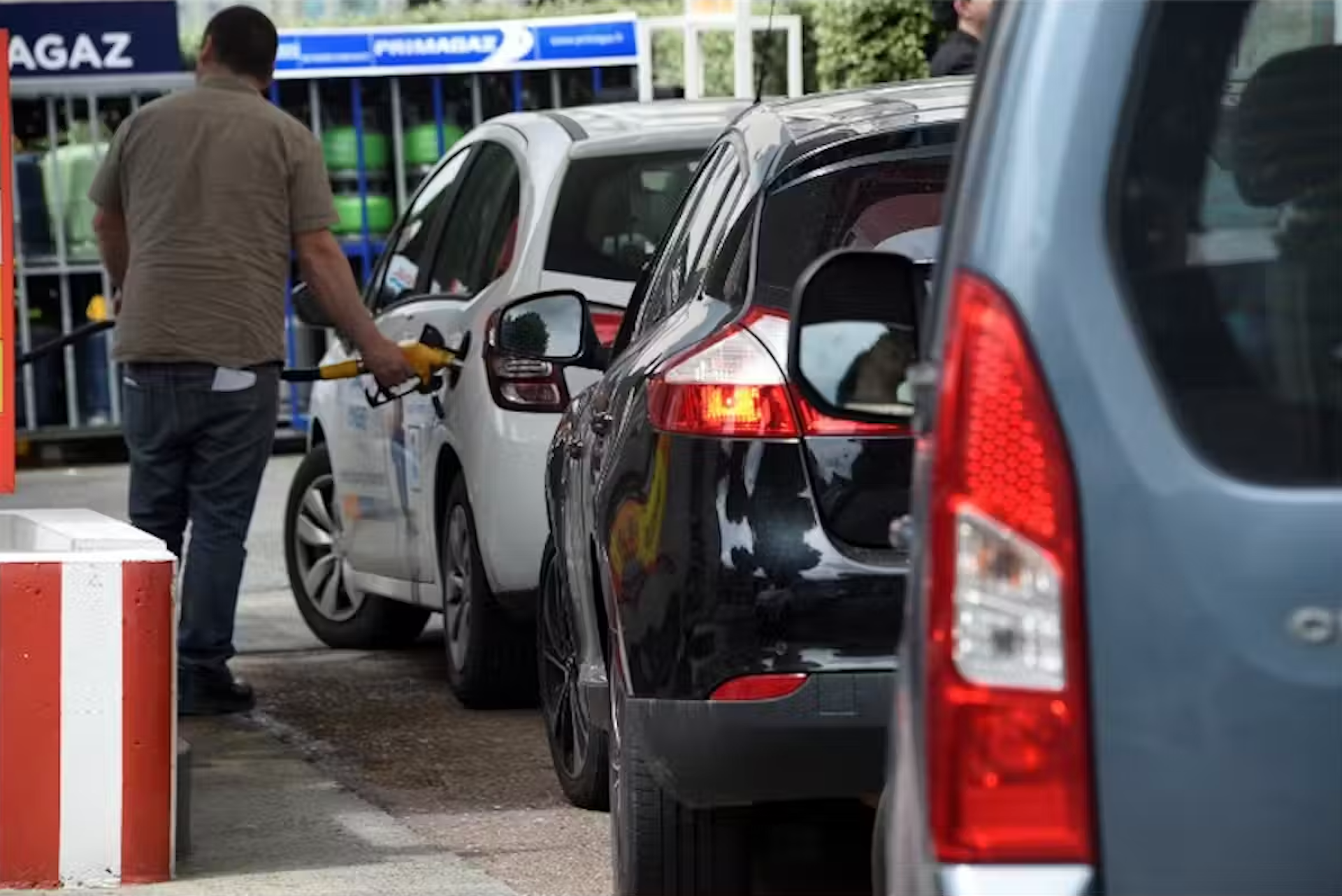 à la station essence un homme fait le plein dans sa voiture