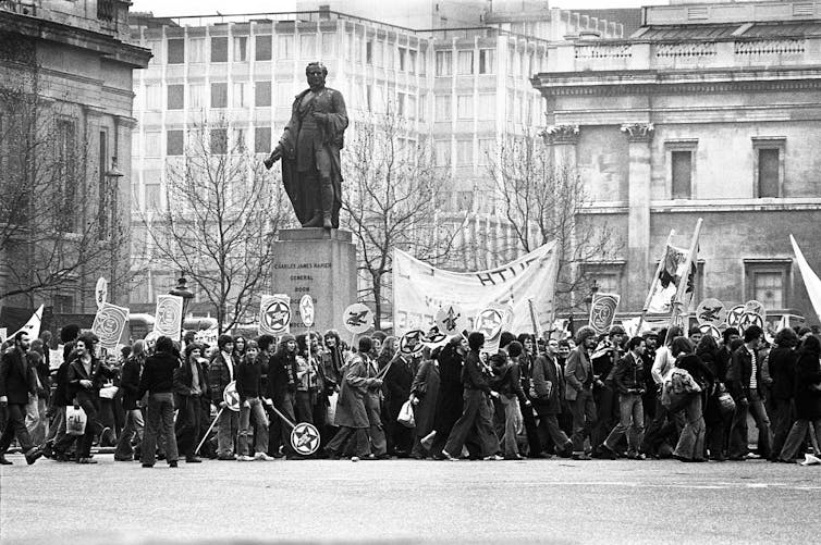 People marching with Rock Against Racism banners in London, black and white photo.