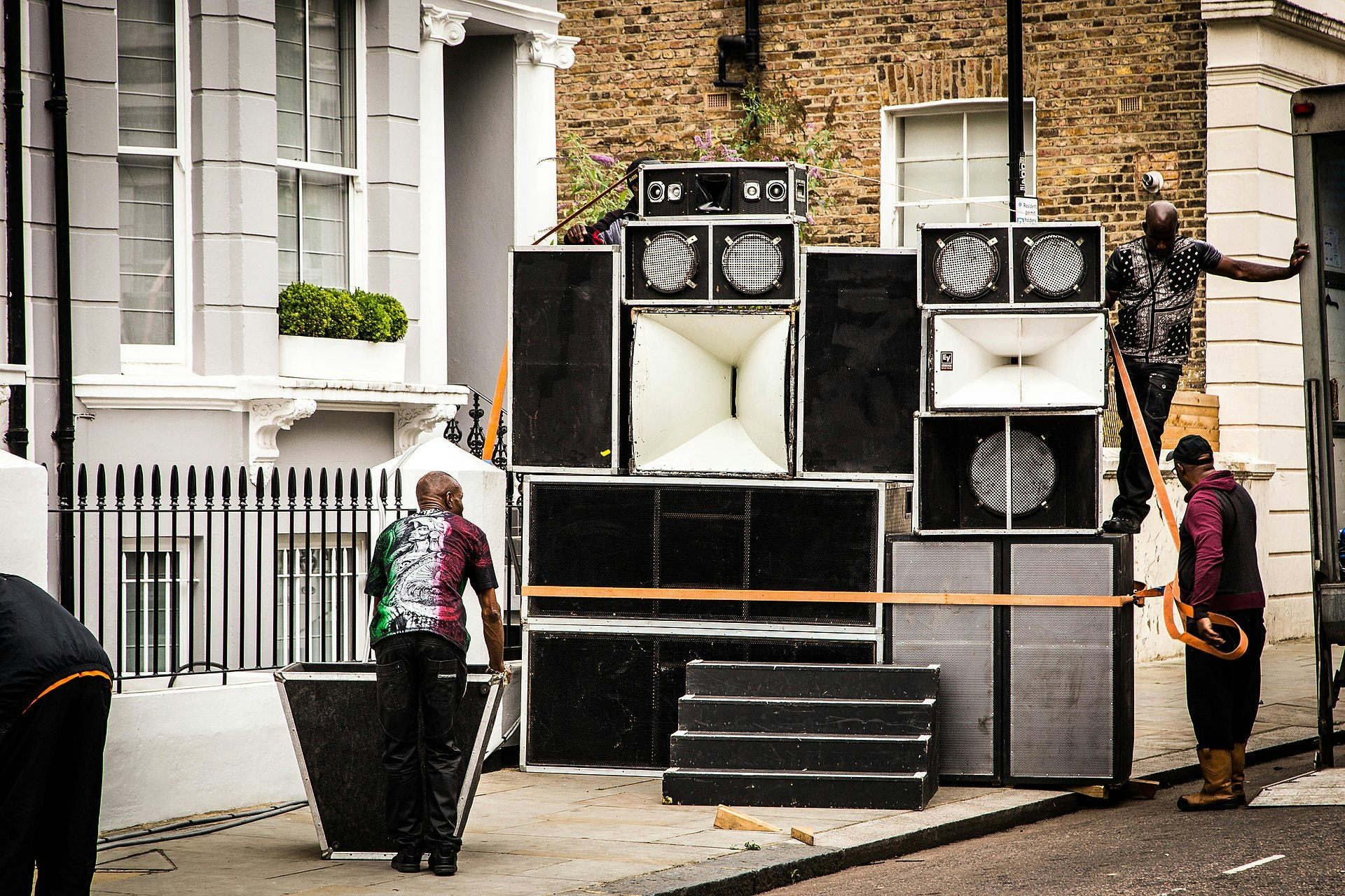 Men setting up a large array of speakers on a street in Notting Hill