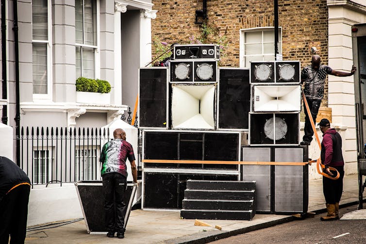 Men setting up a large array of speakers on a street in Notting Hilll.