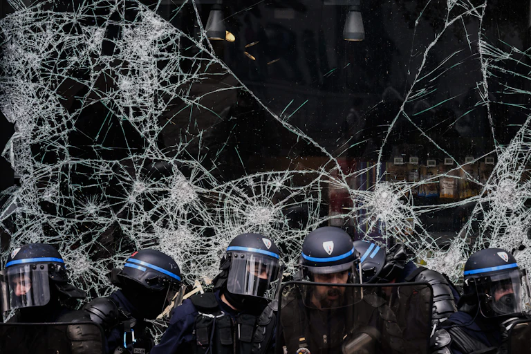 Affrontements entre forces de l'ordre à Lyon, repliés devant une vitrine cassée et manifestants lors du défilé du 1er mai.