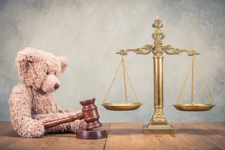 Bronze swords and Teddy bear with wooden gavel on table. Symbols of justice