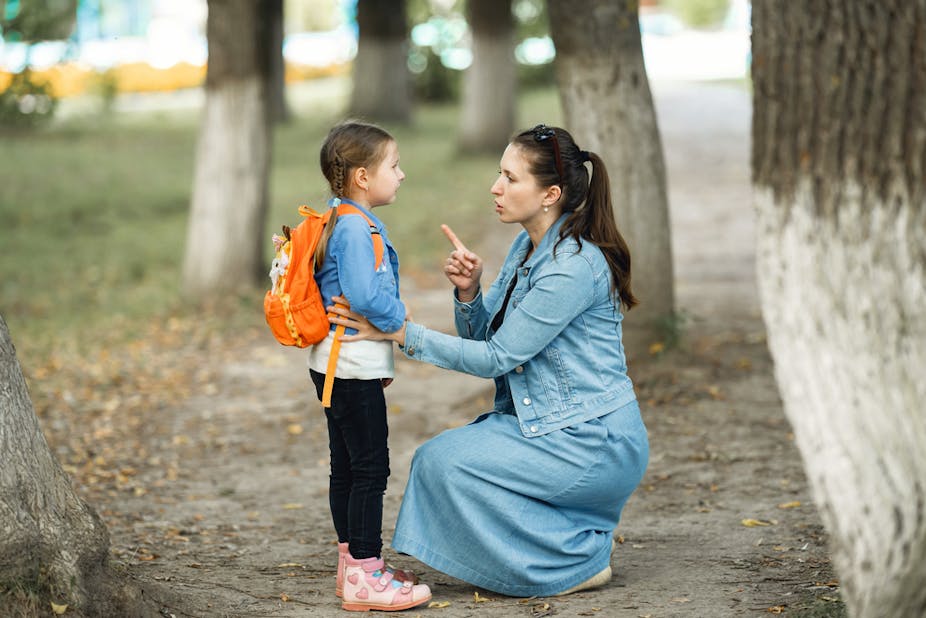 Petite fille avec son cartable qui écoute les recommandations de sa mère avant de partir à l'école