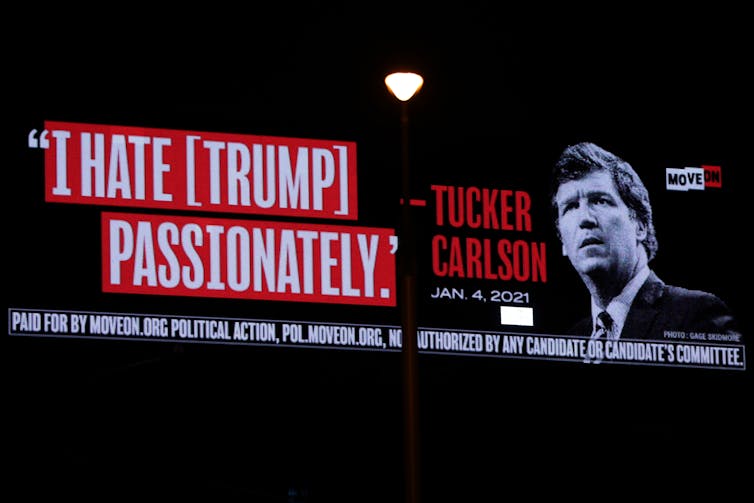 A billboard shows an image of a white man wearing a necktie next to his words that read I hate Trump passionately.