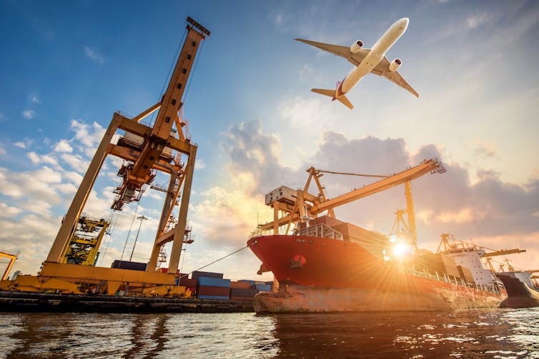 Cargo ship and Cargo plane with working crane bridge in shipyard