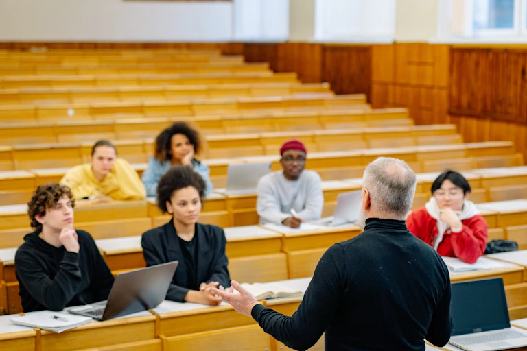 A teacher speaks to a small group of students in a lecture hall.