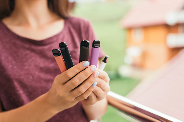 Woman holds different coloured vape pens