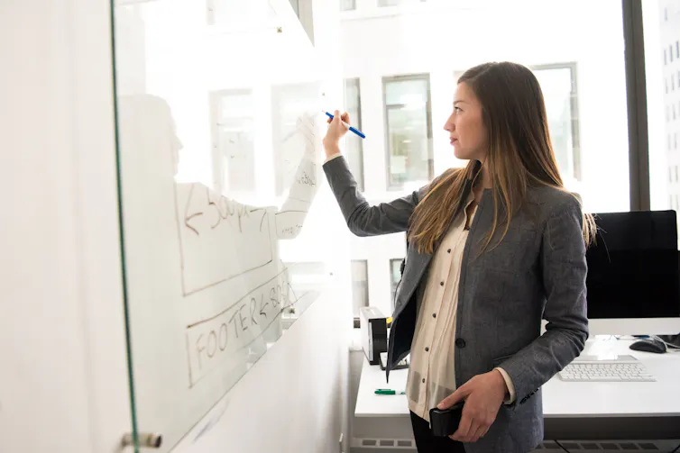 A woman writes on a whiteboard.
