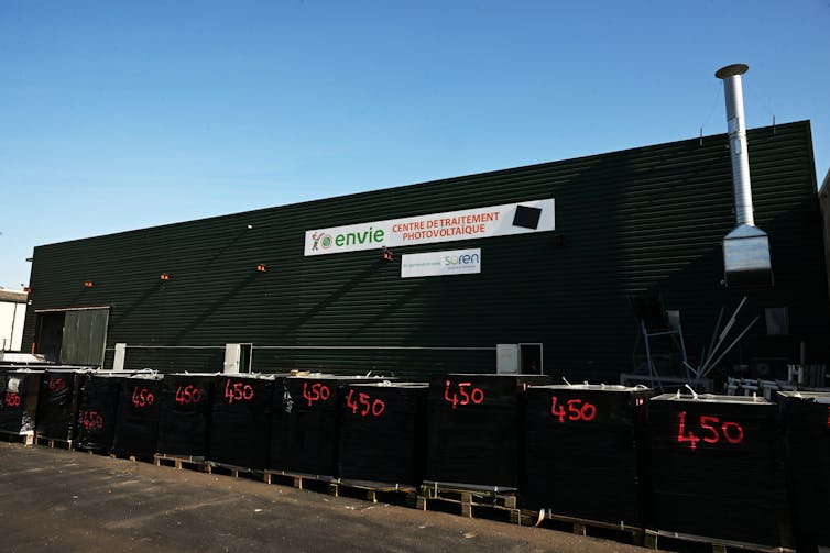 piles of solar panels outside a recycling plant