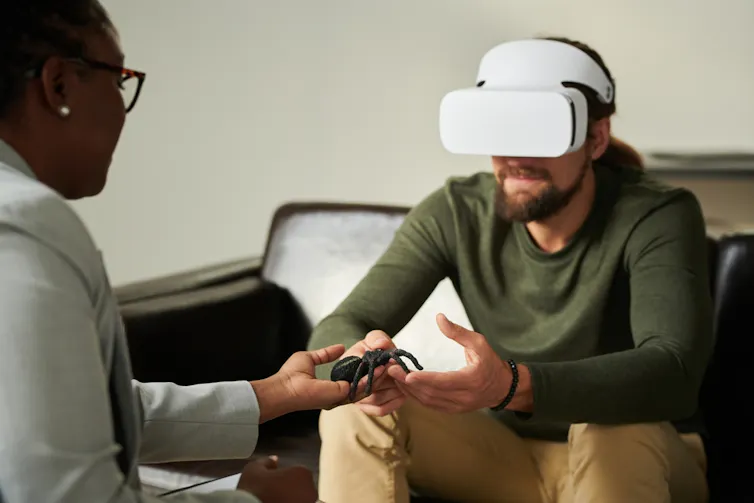 Une thérapeute présente une fausse araignée à un patient portant un casque de réalité virtuelle