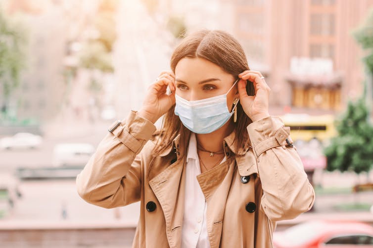 A young woman puts on a mask.