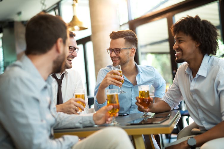 A group of young men in business attire enjoy after work beers.