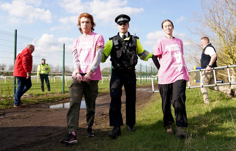 Policeman with two protesters in pink t shirts