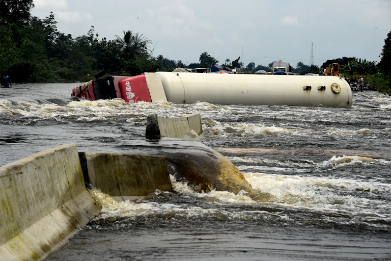 A fallen tanker lies across a heavily flooded road.