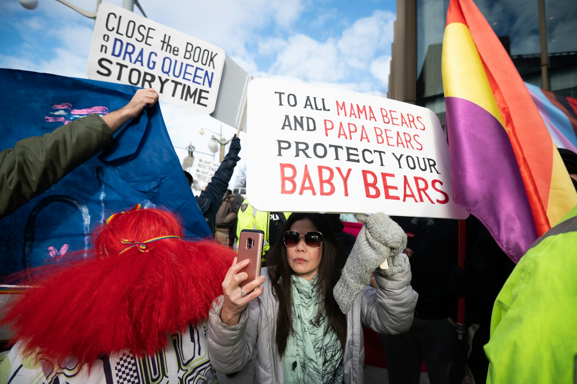 A woman wearing sunglasses carrying an anti-lgbt placard at a protest