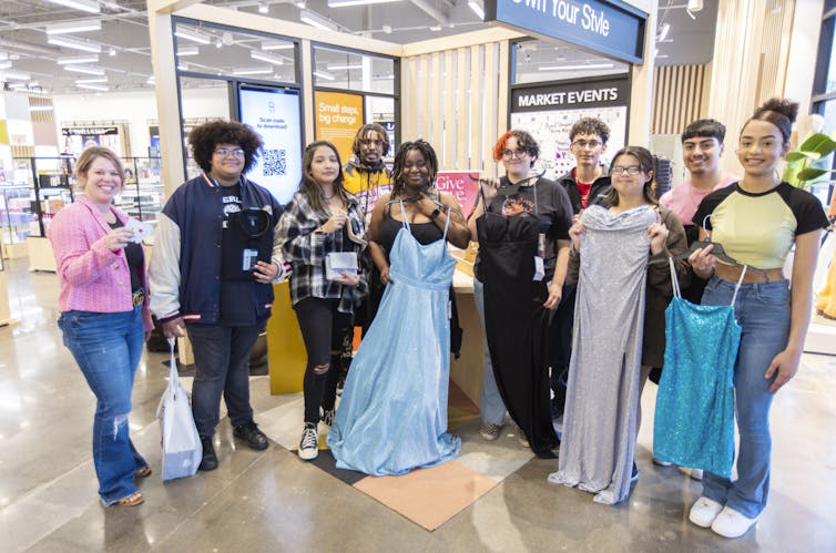group of young people hold dresses are suits in a department store