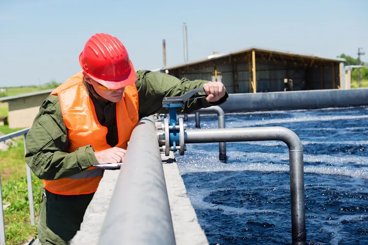 Un ingénieur contrôlant la qualité de l’eau, réservoir de boues activées aérées dans une usine de traitement des eaux usées