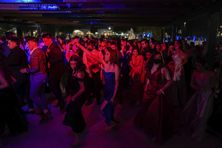 a crowd of young people dance in a dark room with red light