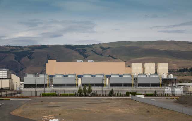 a large industrial building with hills in the background