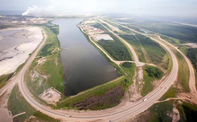 A highway loops around a tailing pond.