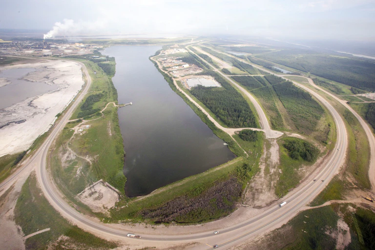 A highway loops around a tailing pond.