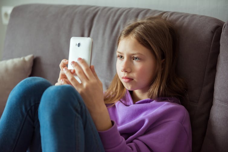 Girl in purple jumper looks at mobile phone