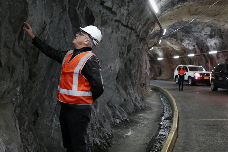man in orange vest touches tunnel wall