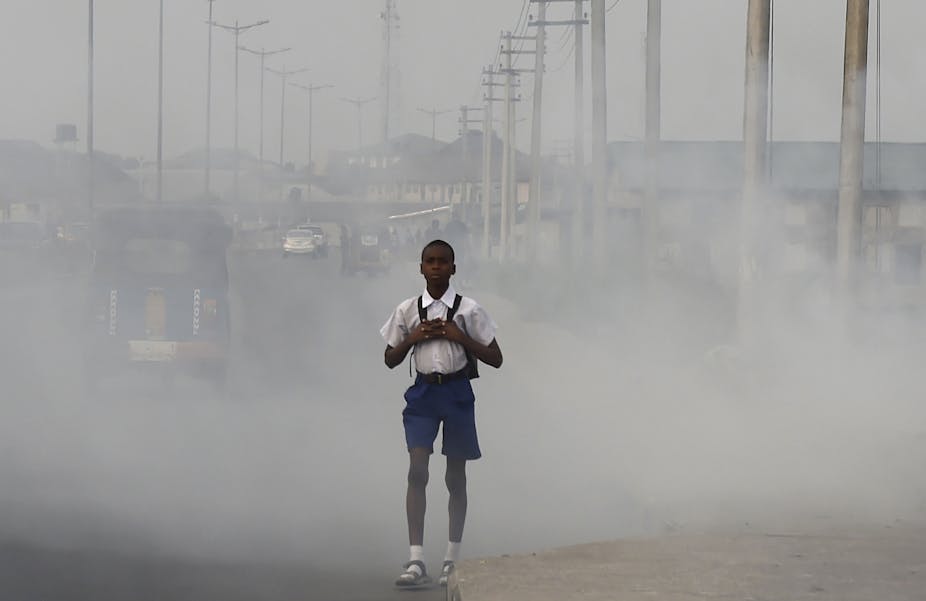 Boy wearing backpack walking on a street covered with smog