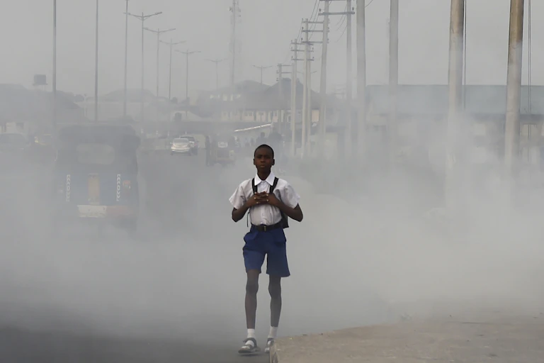 Boy wearing backpack walking on a street covered with smog