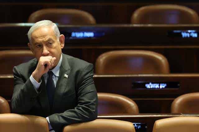 Israel's prime minister, Benjamin Netanyahu sits holding his hand to his mouth.