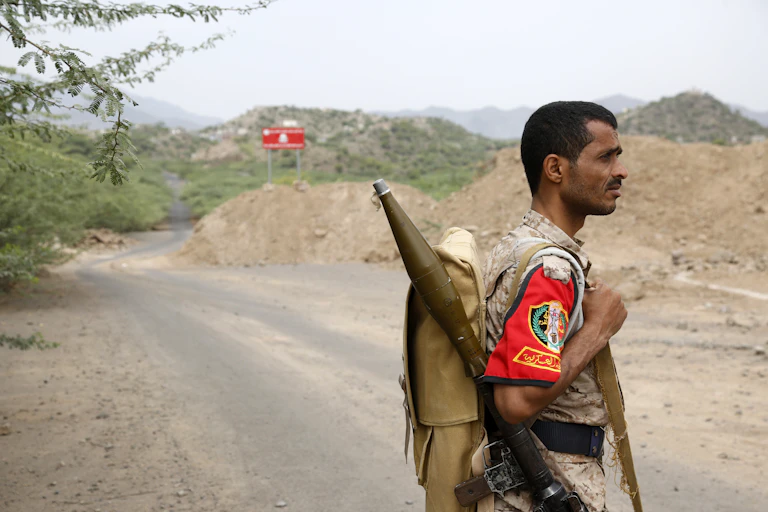 A man in afatigues has a rocket launcher slung over his shoulder.